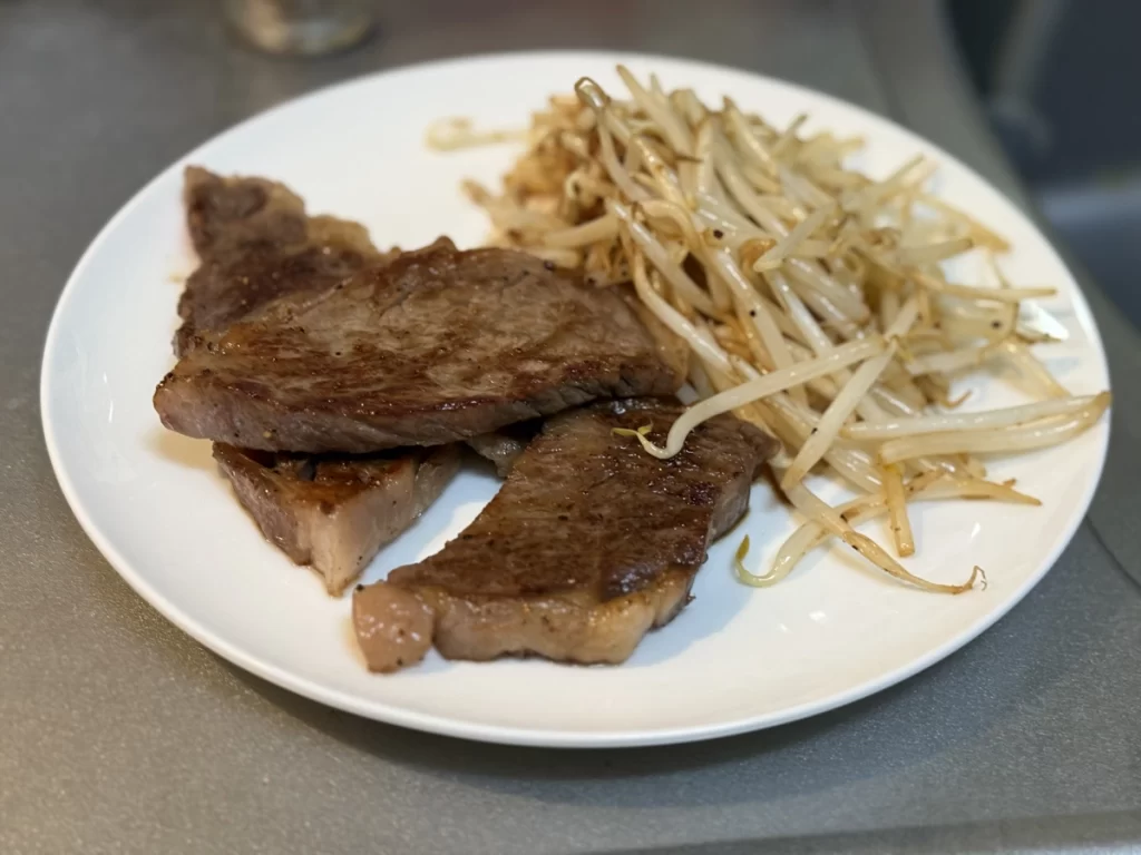 鉄フライパンで調理したステーキともやしの完成品